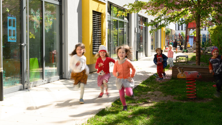 Rennende Kinder in einem Garten einer KiTa